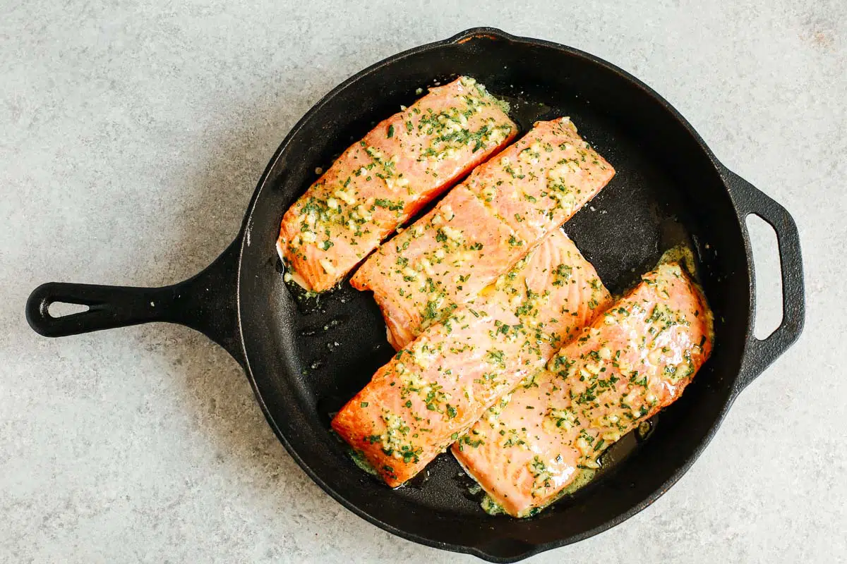 cast iron skillet with raw salmon fillets with mustard sauce