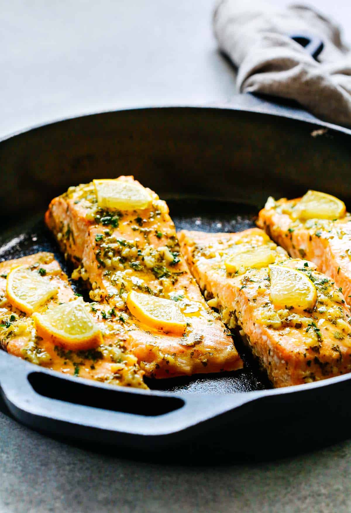 cooked salmon topped with lemon slices in a large skillet