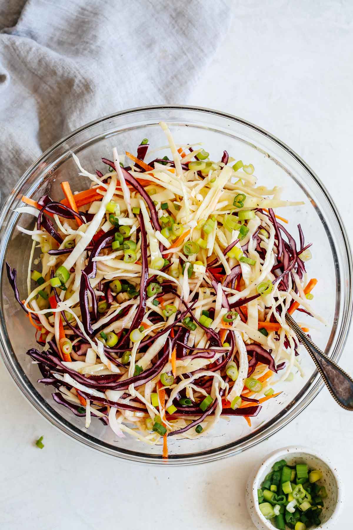 shredded vegetables and a spoon in a bowl sitting on a white towel