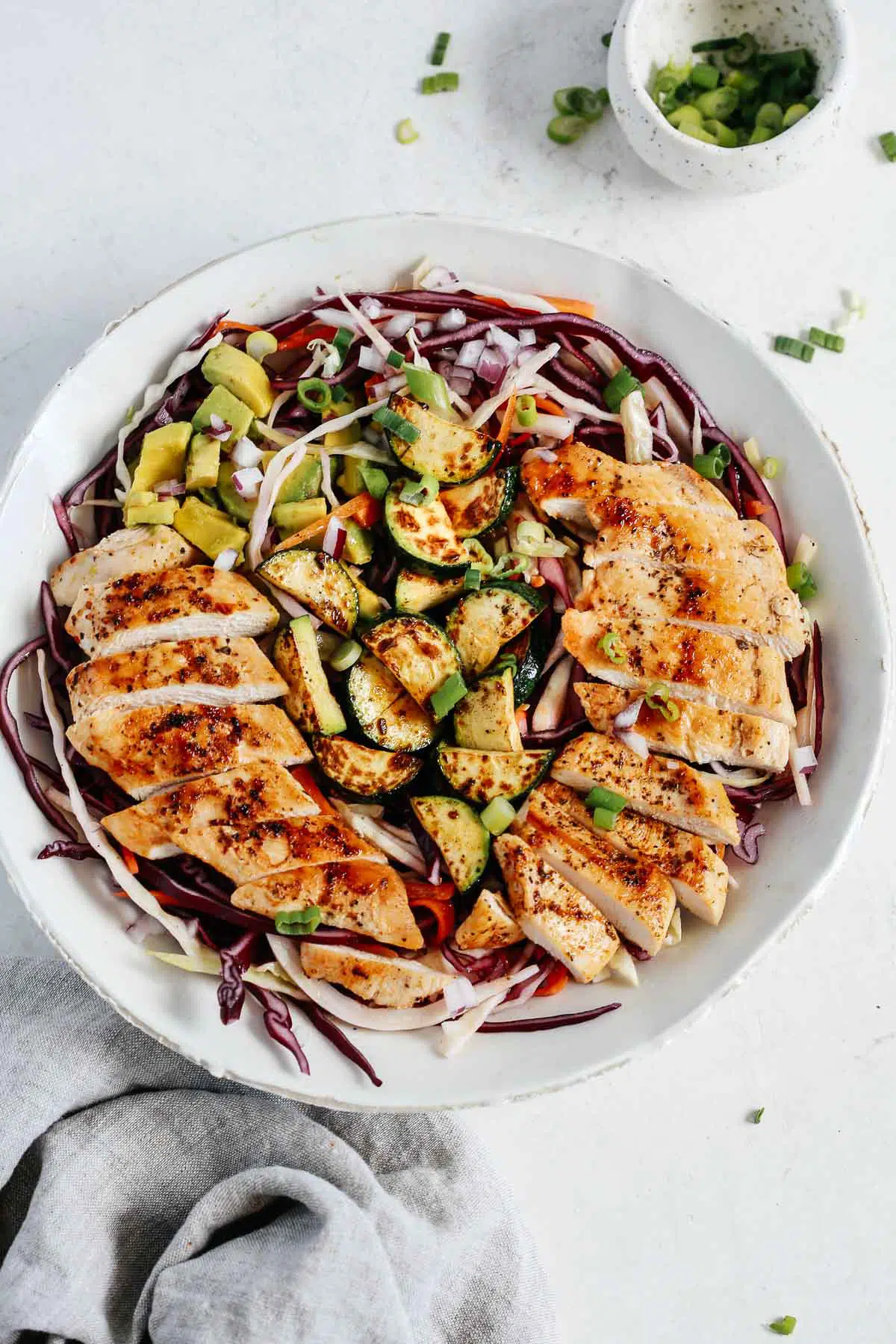 Overhead view of a cabbage salad with chicken in a white bowl.