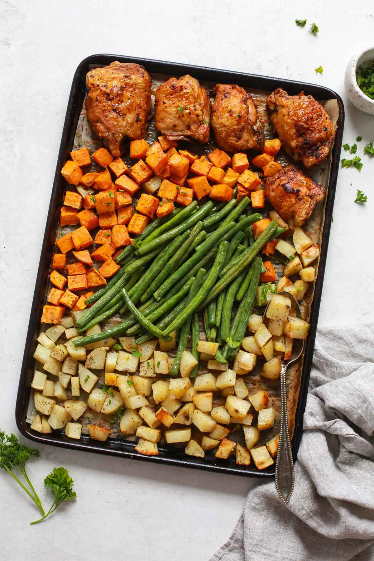 overhead view of a baking sheet containing vegetables and chicken thighs 