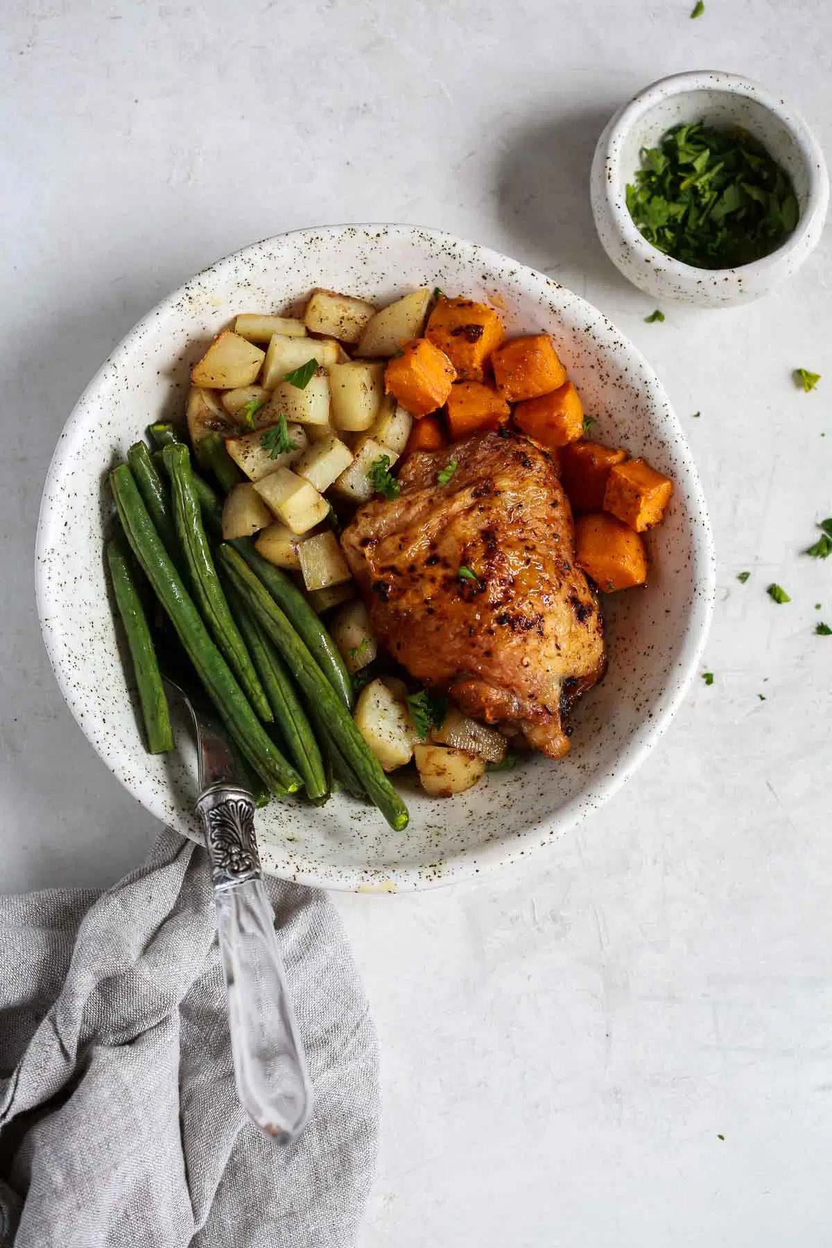 overhead view of a white bowl containing chicken with vegetables 