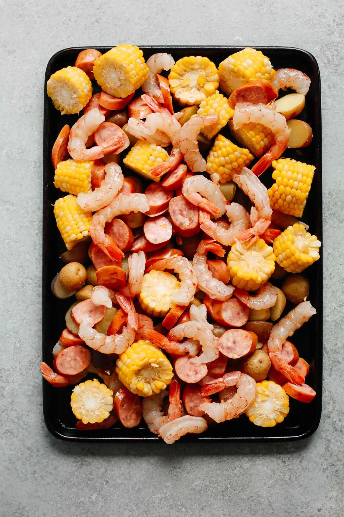 baking sheet with shrimp, sausage, corn, and pototoes