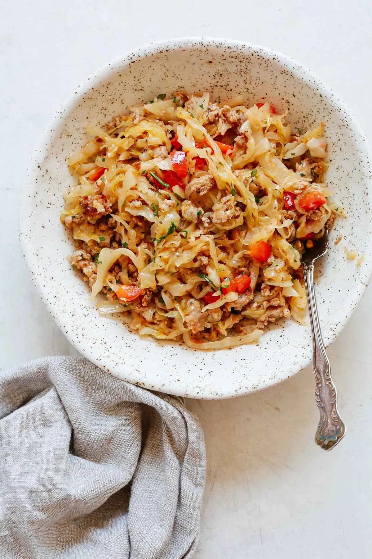 cooked cabbage and sausage skillet in a spotted bowl with a fork