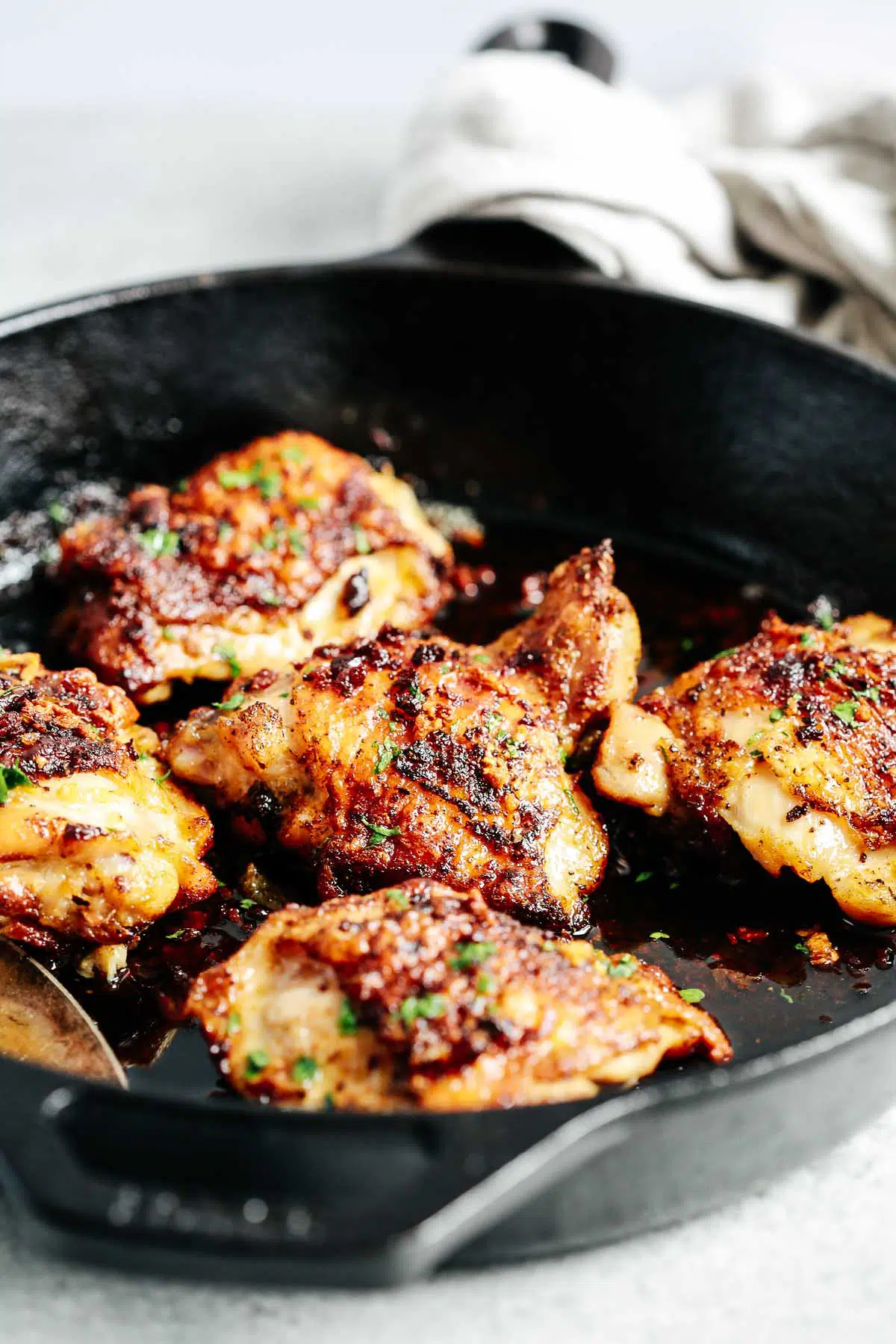 closeup view of cooked chicken thighs in a skillet with butter sauce