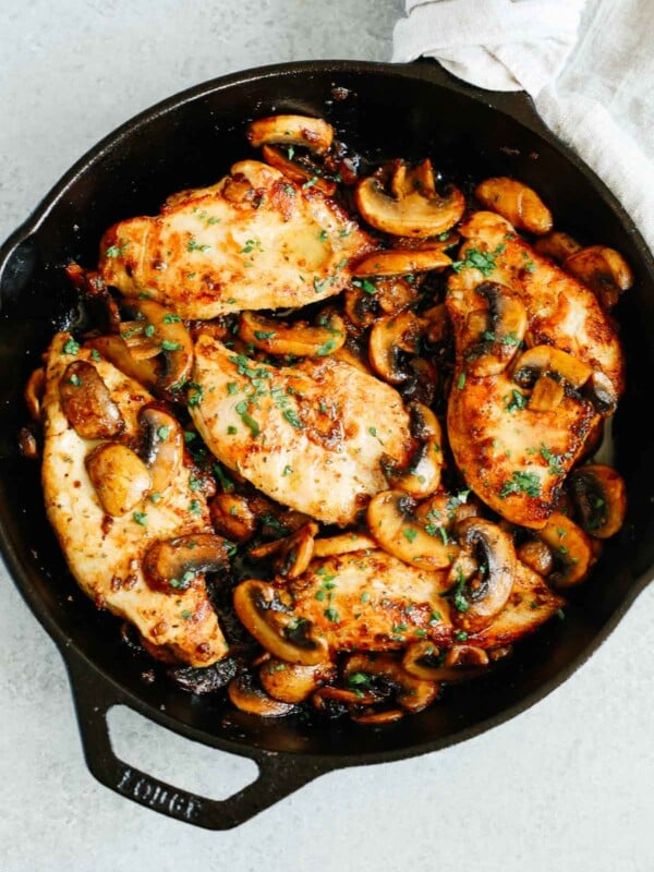 overhead photo of cooked chicken breasts and mushrooms in a cast iron skillet