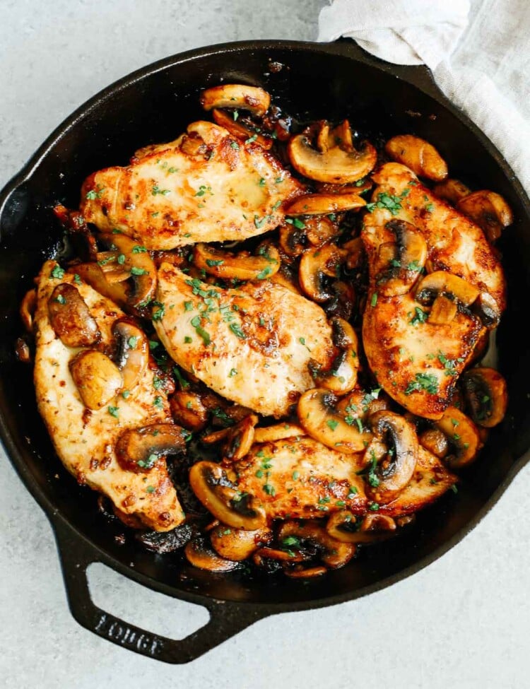 overhead photo of cooked chicken breasts and mushrooms in a cast iron skillet