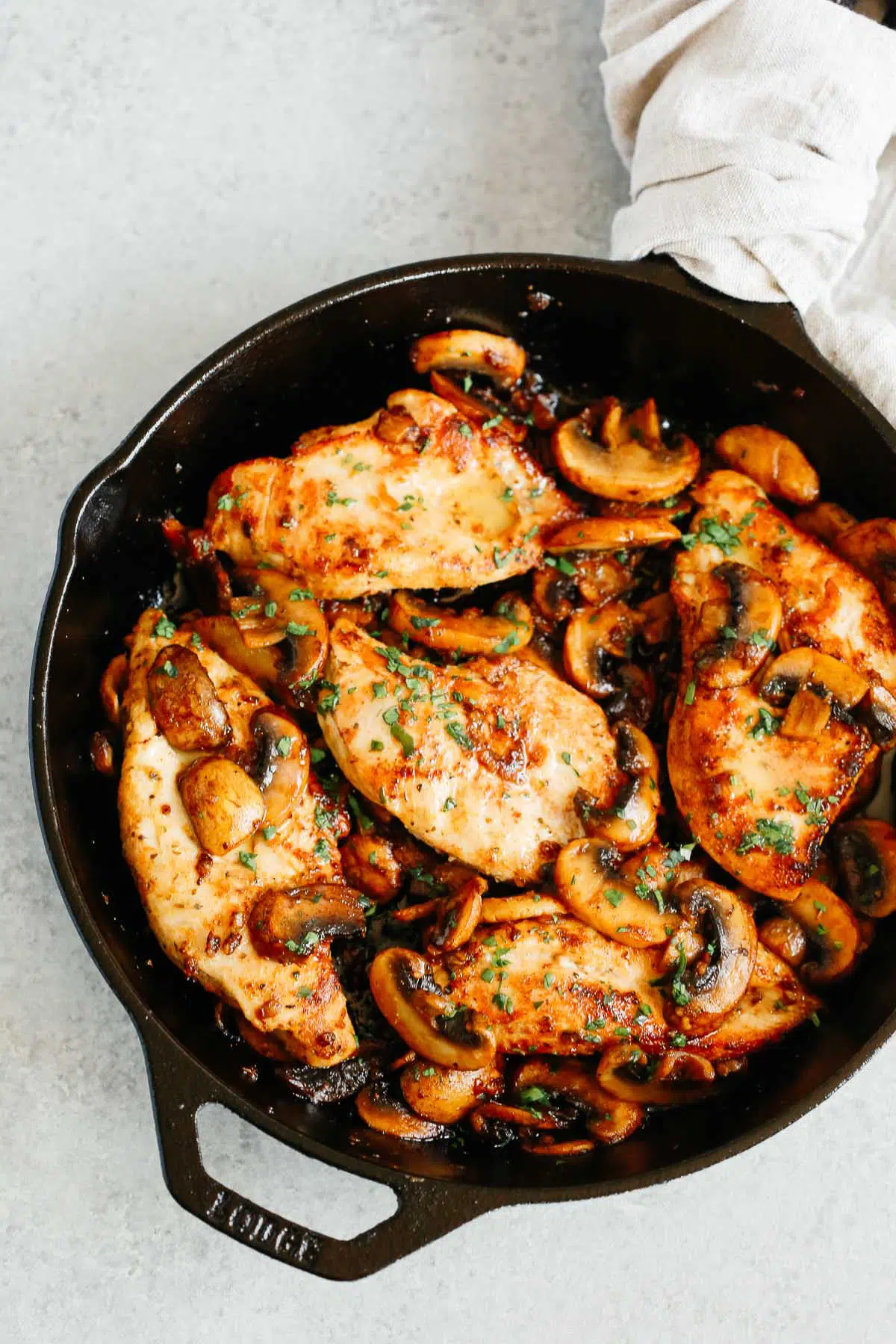 overhead photo of cooked chicken breasts and mushrooms in a cast iron skillet