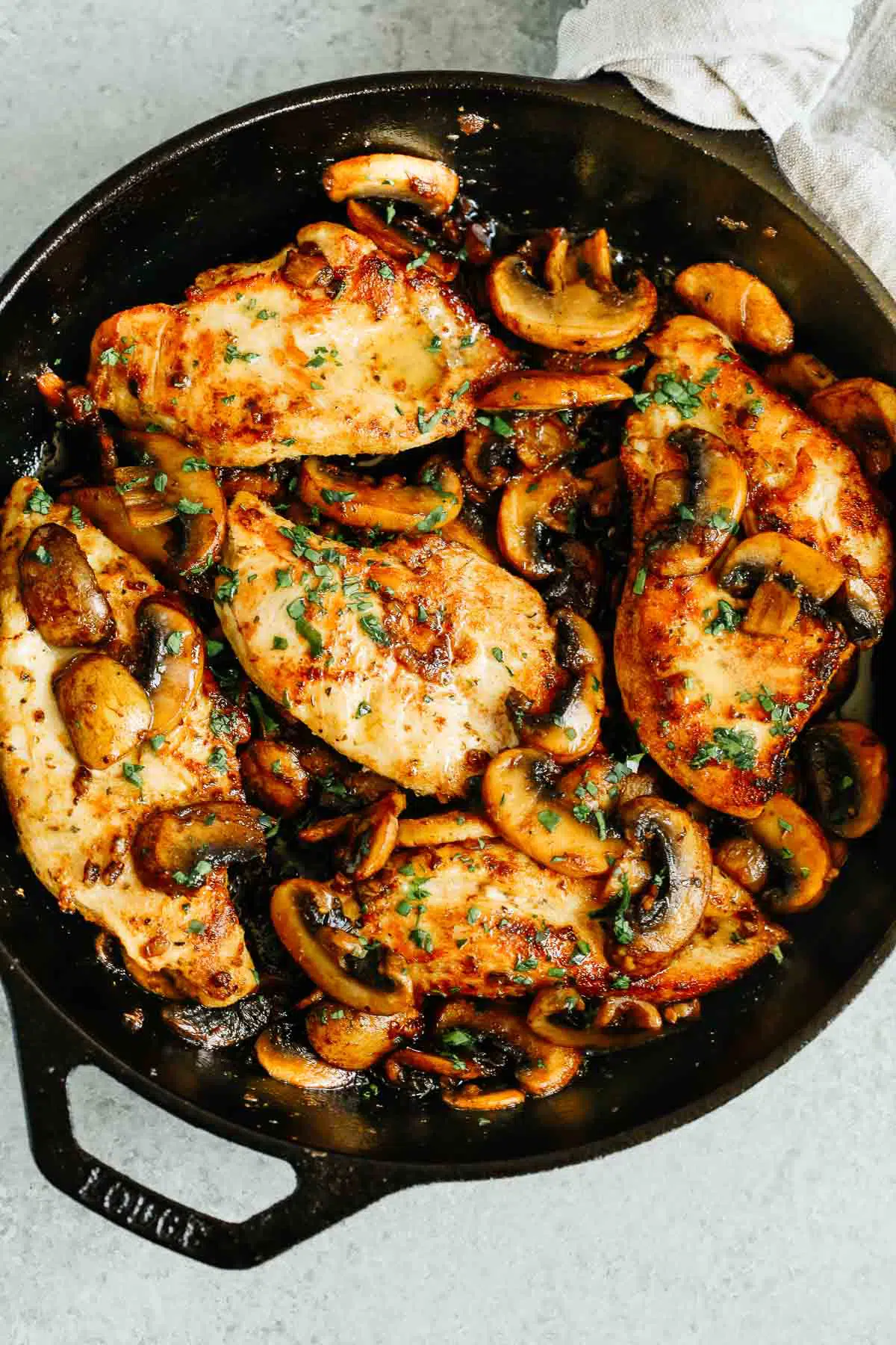 overhead photo of cooked chicken breasts and mushrooms in a cast iron skillet