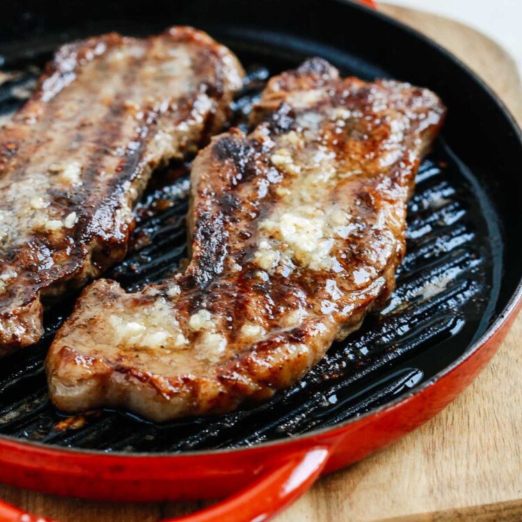cooked steaks with garlic butter in a skillet on a cutting board