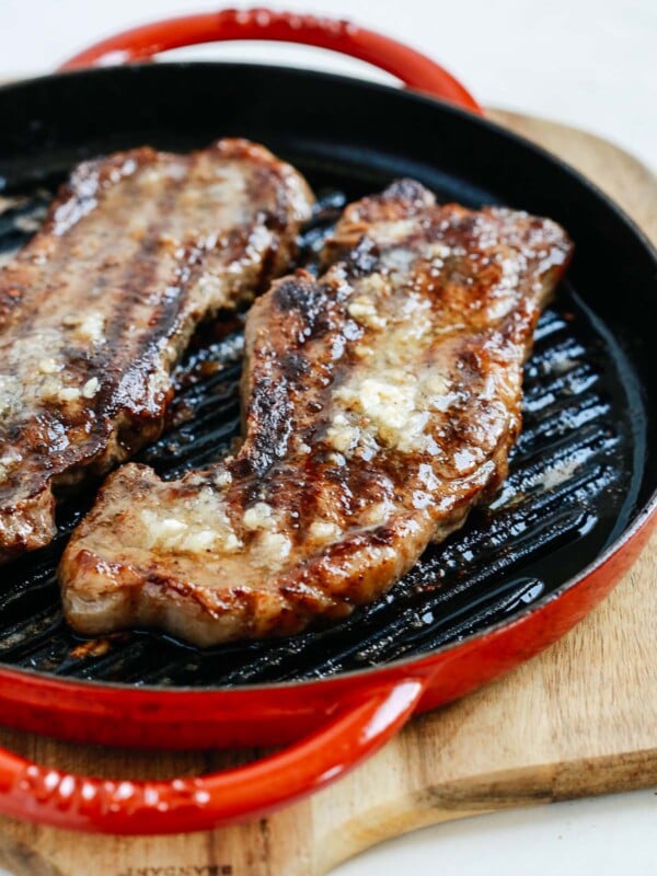 cooked steaks with garlic butter in a skillet on a cutting board