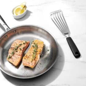 overhead view of a fish fillet inside of a skillet and a spatula beside the skillet