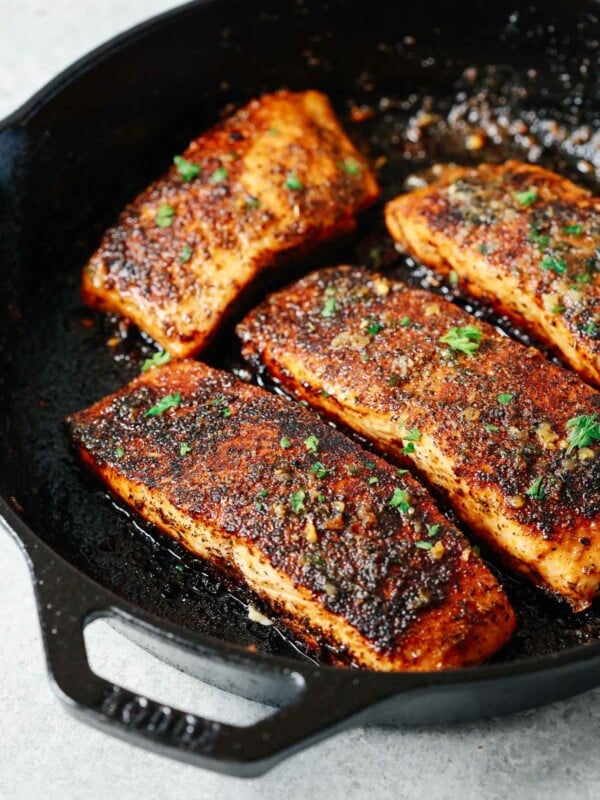 four blackened salmon fillets in a cast iron skillet