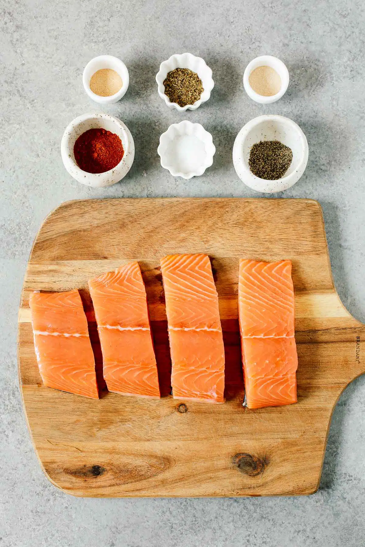 overhead image: 4 raw fish fillets and 6 small prep bowls with spices to make a blackened salmon recipe