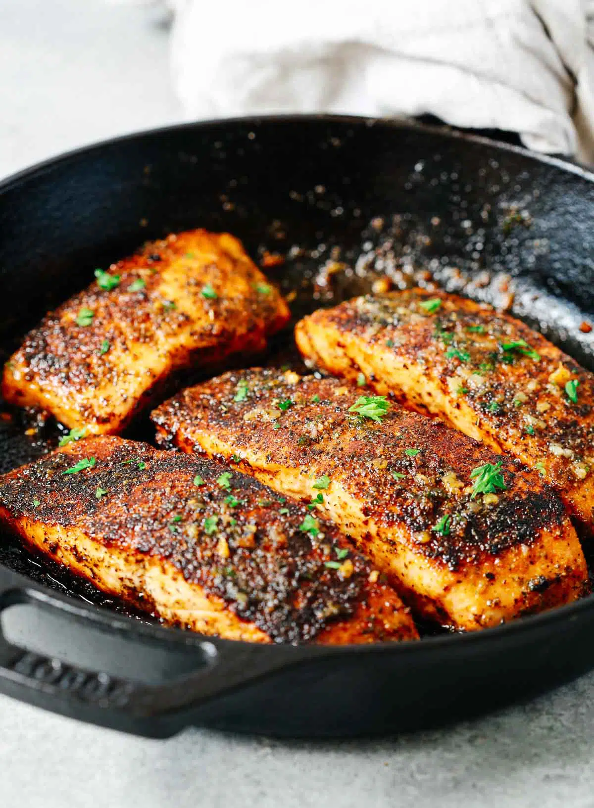 cooking four heavily seasoned fish fillets in a cast iron skillet