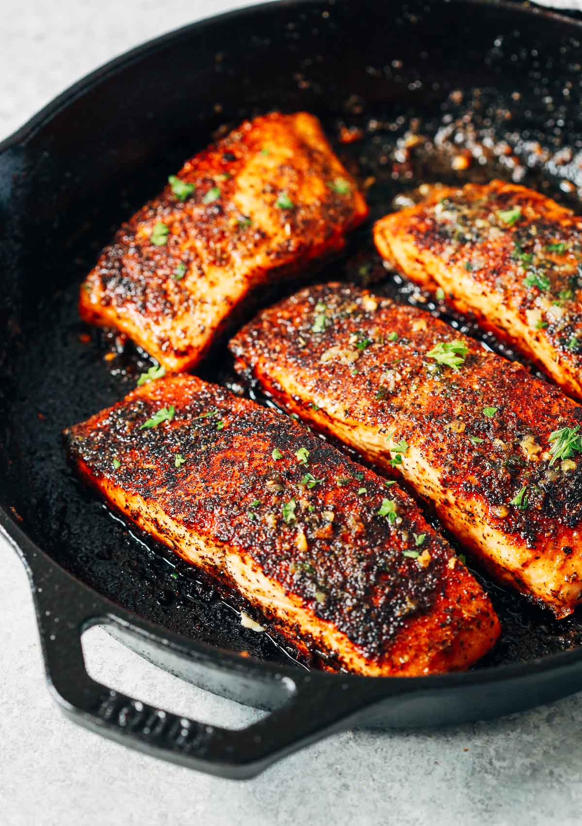 overhead view of a white skillet containing Blackened salmon 