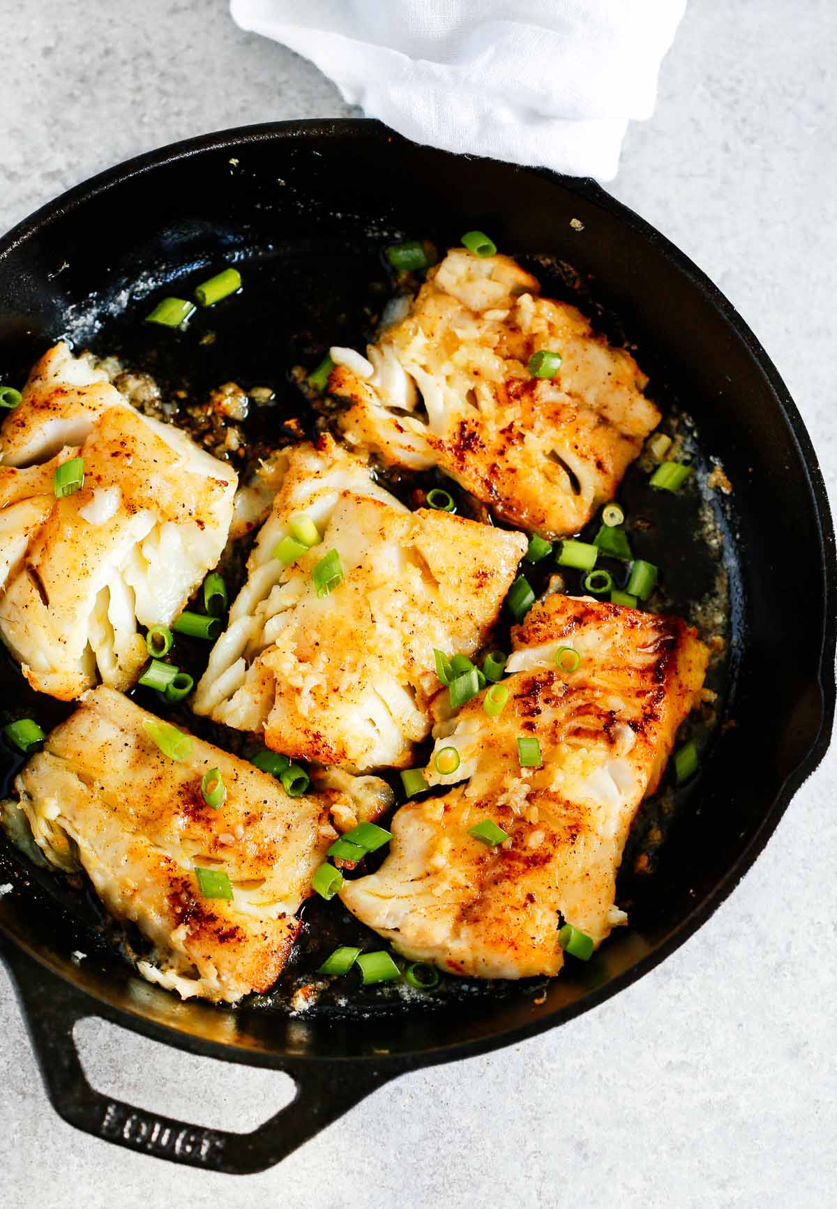 pieces of garlic butter cod cooking in cast iron skillet - gluten-free dinner recipes
