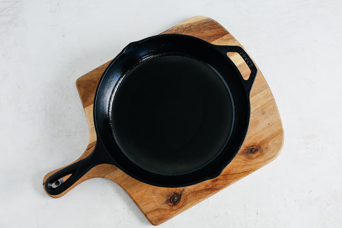 overhead image: well seasoned cast iron skillet on a wooden cutting board