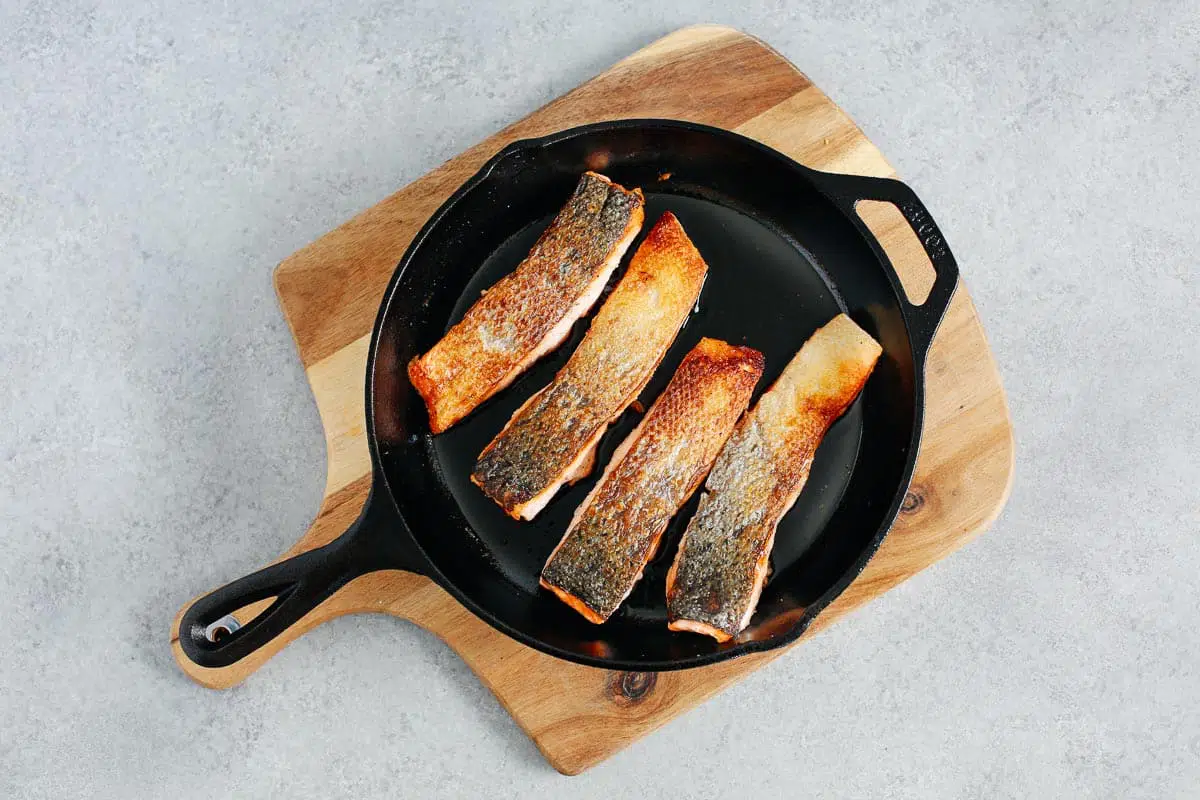 4 salmon fillets with crispy skin in a cast iron skillet