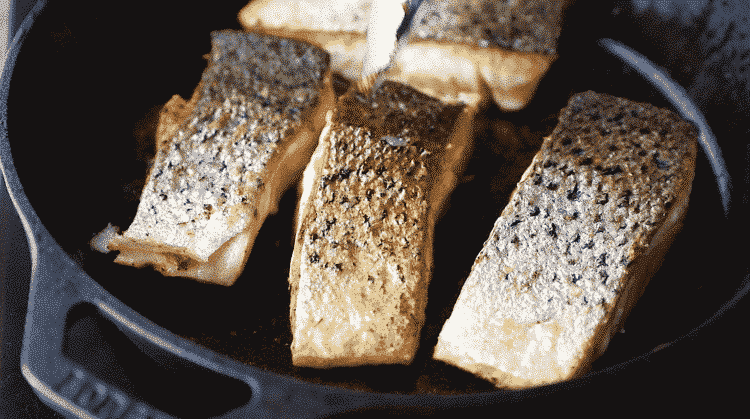 close up of crispy skin salmon inside of a cast iron skillet
