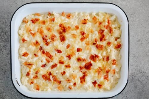 cauliflower casserole ready to be baked in a white baking dish.
