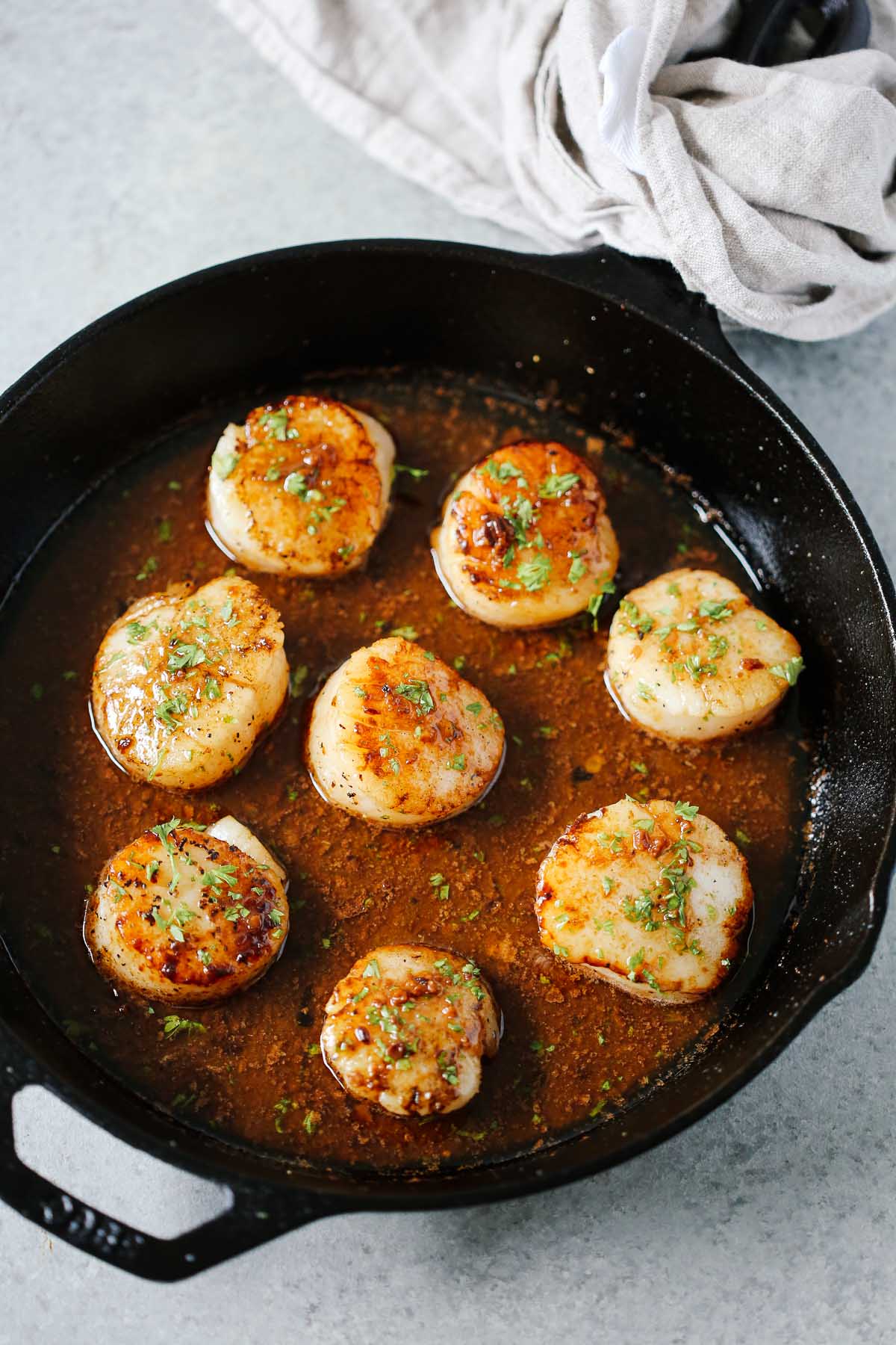overhead view of a white skillet containing Garlic Butter Scallops