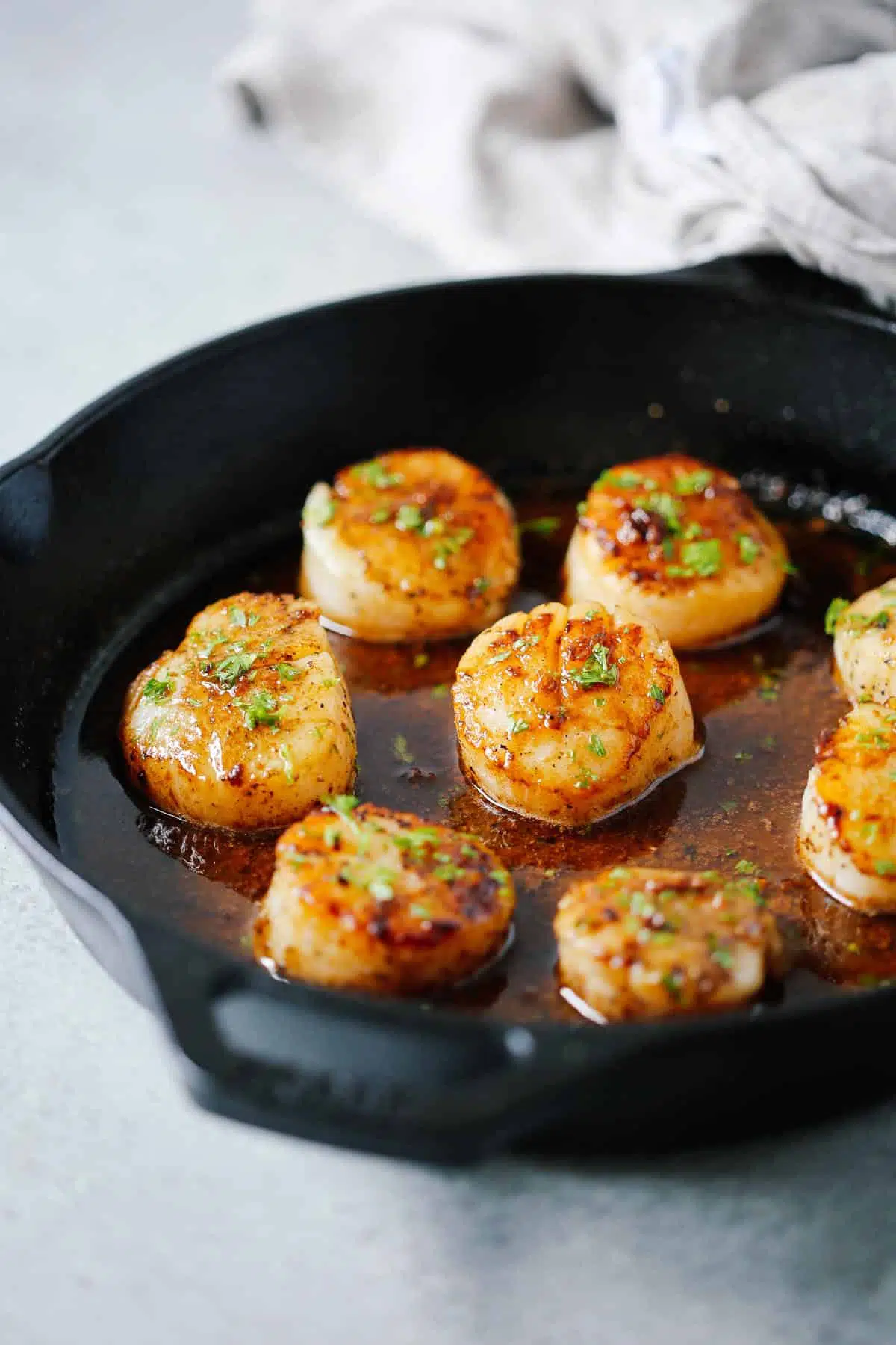close up of garlic butter scallops in a cast ion skillet