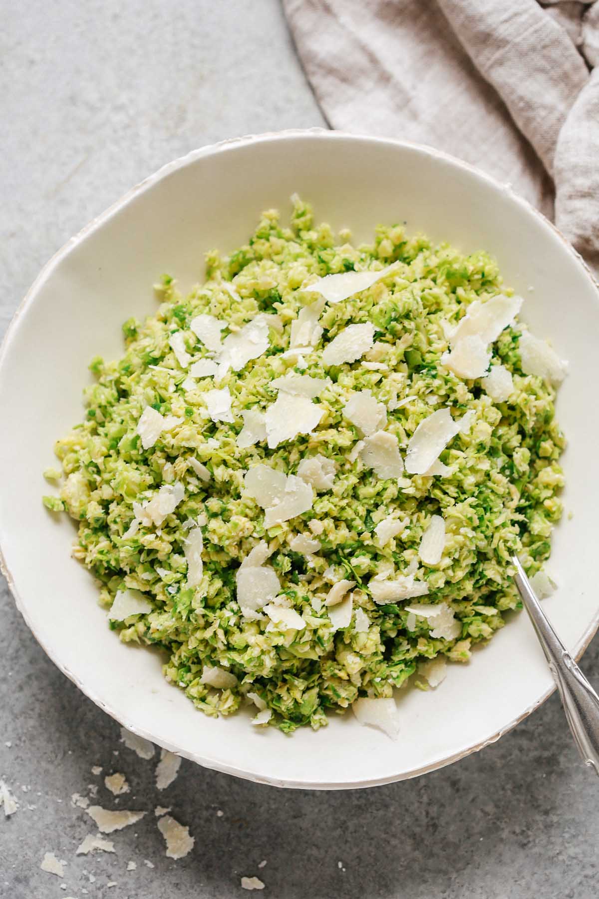 close up of a Parmesan Brussels Sprouts Salad with a spoon and shaved parmesan on top