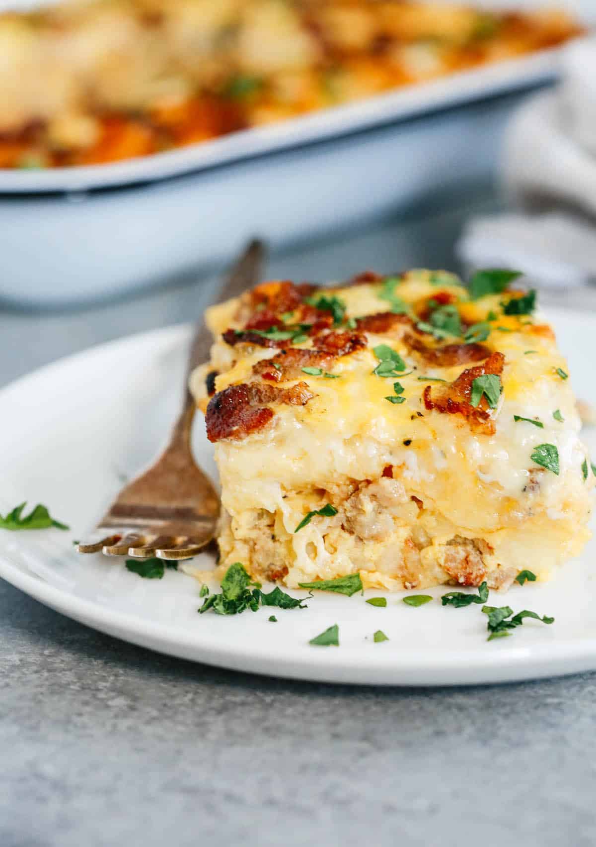 a slice of Sausage and Potato Breakfast Casserole on a plate with a fork