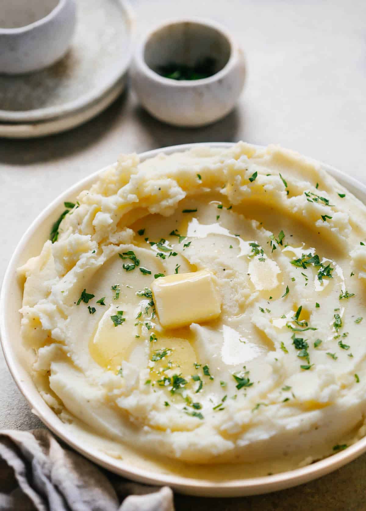 Angled image of creamy mashed potatoes recipe with butter melted on top.