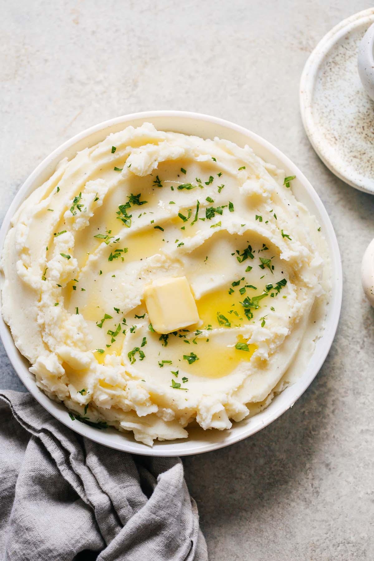 A large bowl of mashed potatoes with butter melted on top.