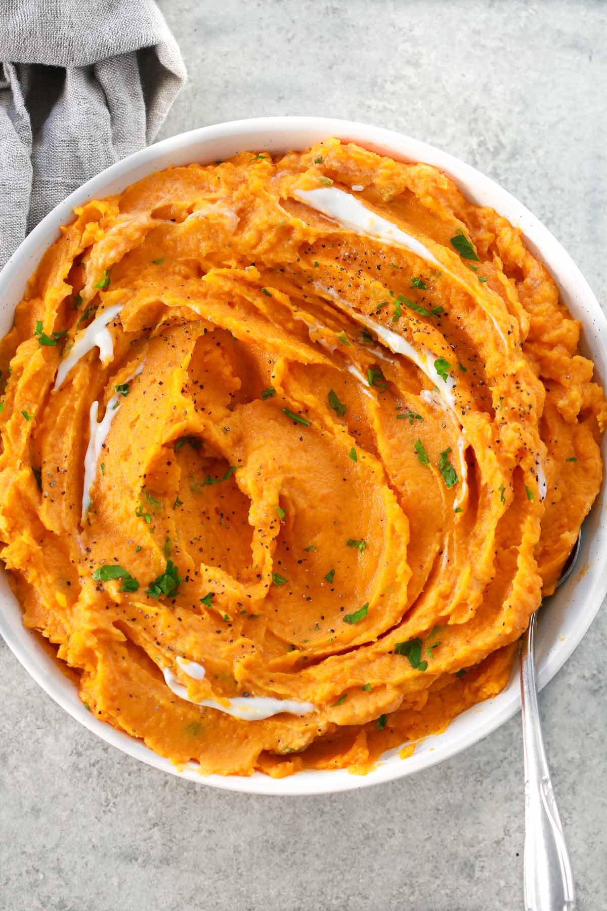 Overhead photo of a bowl of creamy savory mashed sweet potatoes with a spoon inside of it. 