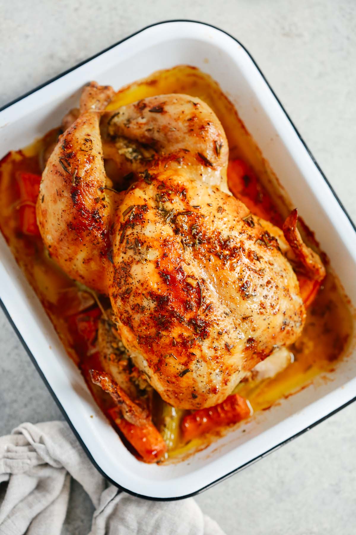 Overhead image of roasted whole chicken inside of a roasting pan