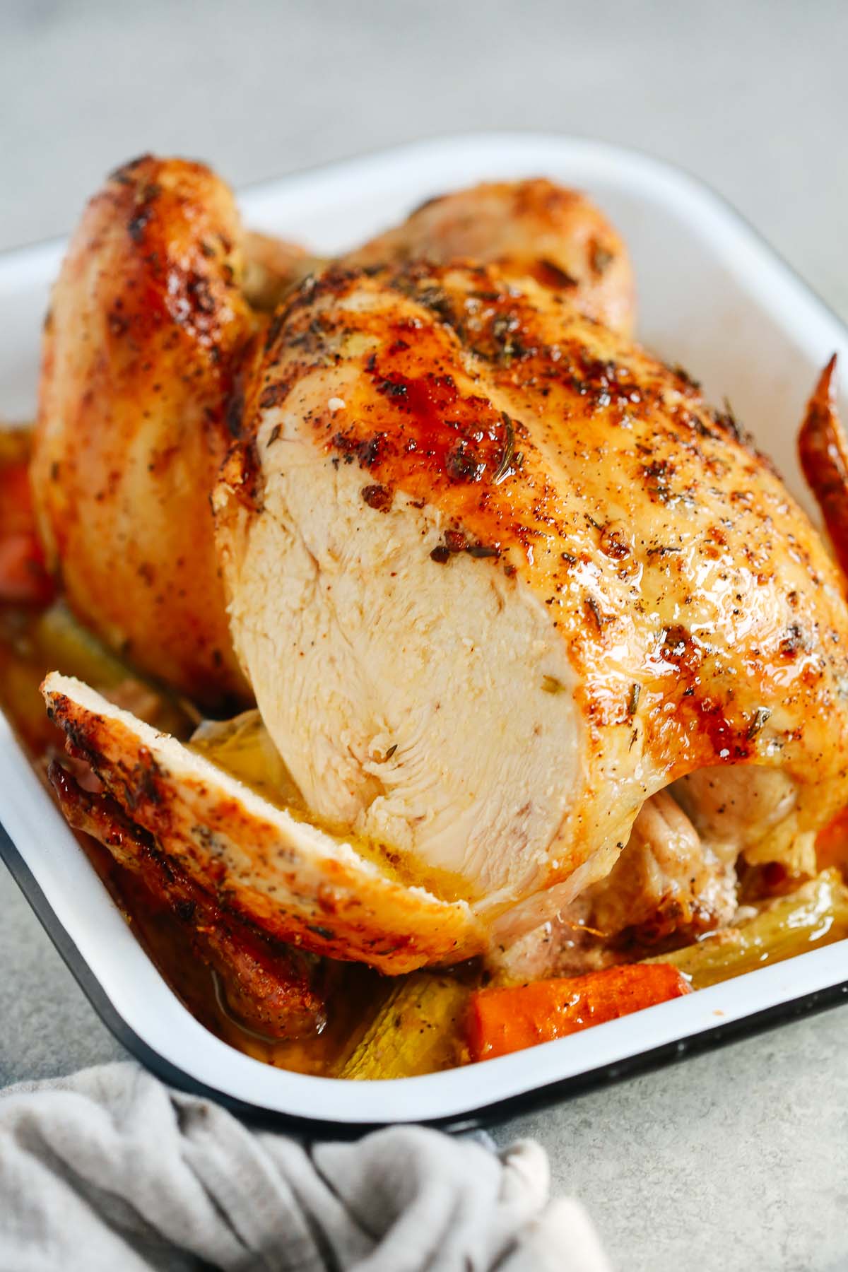 Close up photo of roasted whole chicken with part of the breast sliced. 