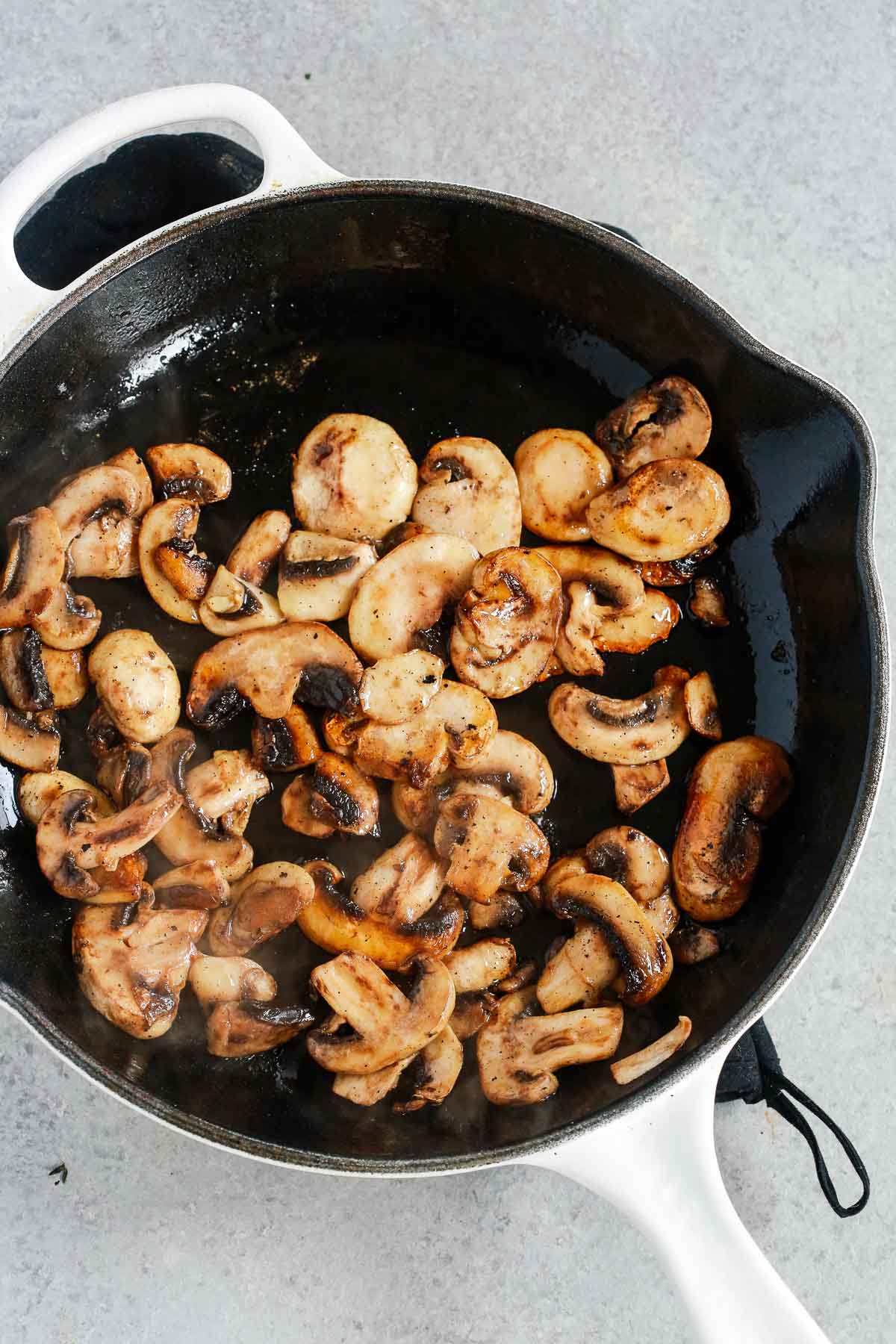 Overhead image of mushrooms sautéing in a cast iron pan