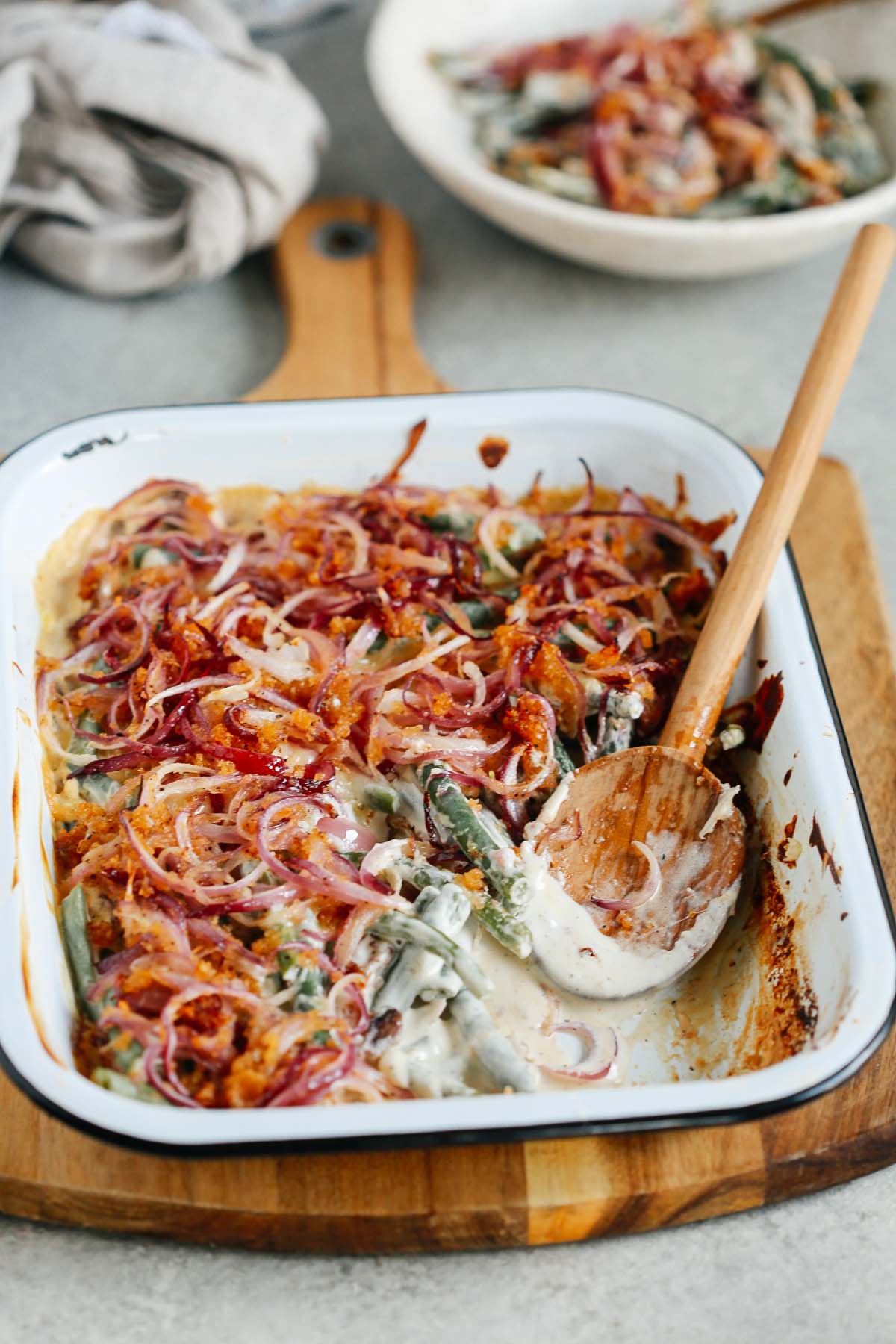 Angled image of Healthier Green Bean Casserole Recipe with a wooden spoon scooping a portion out.