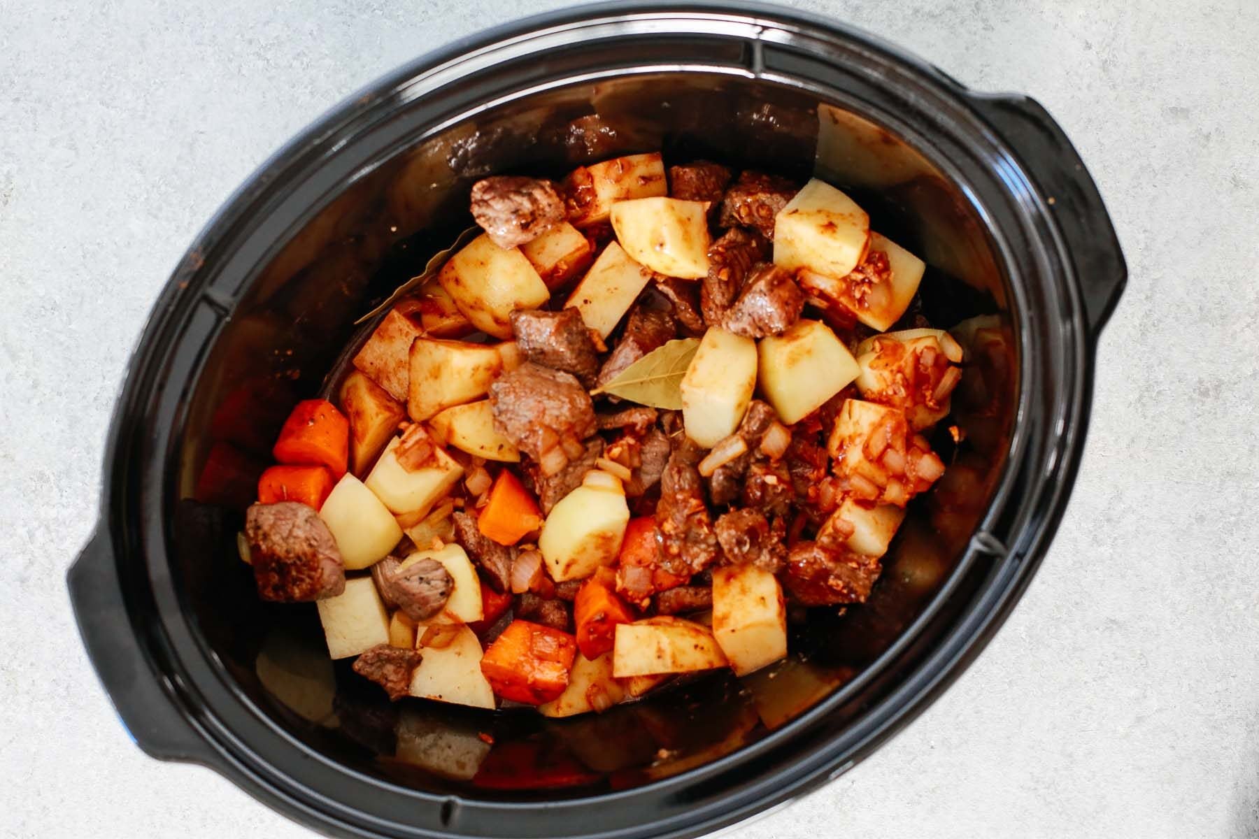 Healthy slow cooker beef stew inside of a black slow cooker.