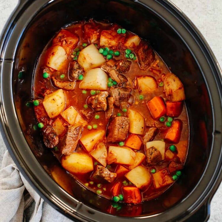 Healthy slow cooker beef stew inside of a black slow cooker.