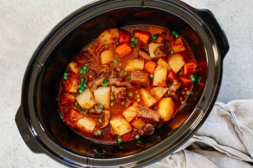 Healthy slow cooker beef stew inside of a black slow cooker.