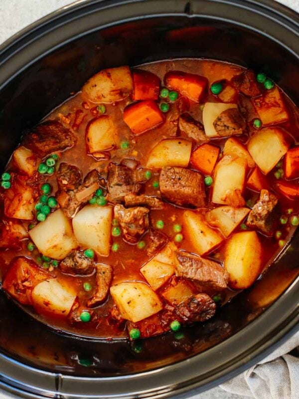 Healthy slow cooker beef stew inside of a black slow cooker.
