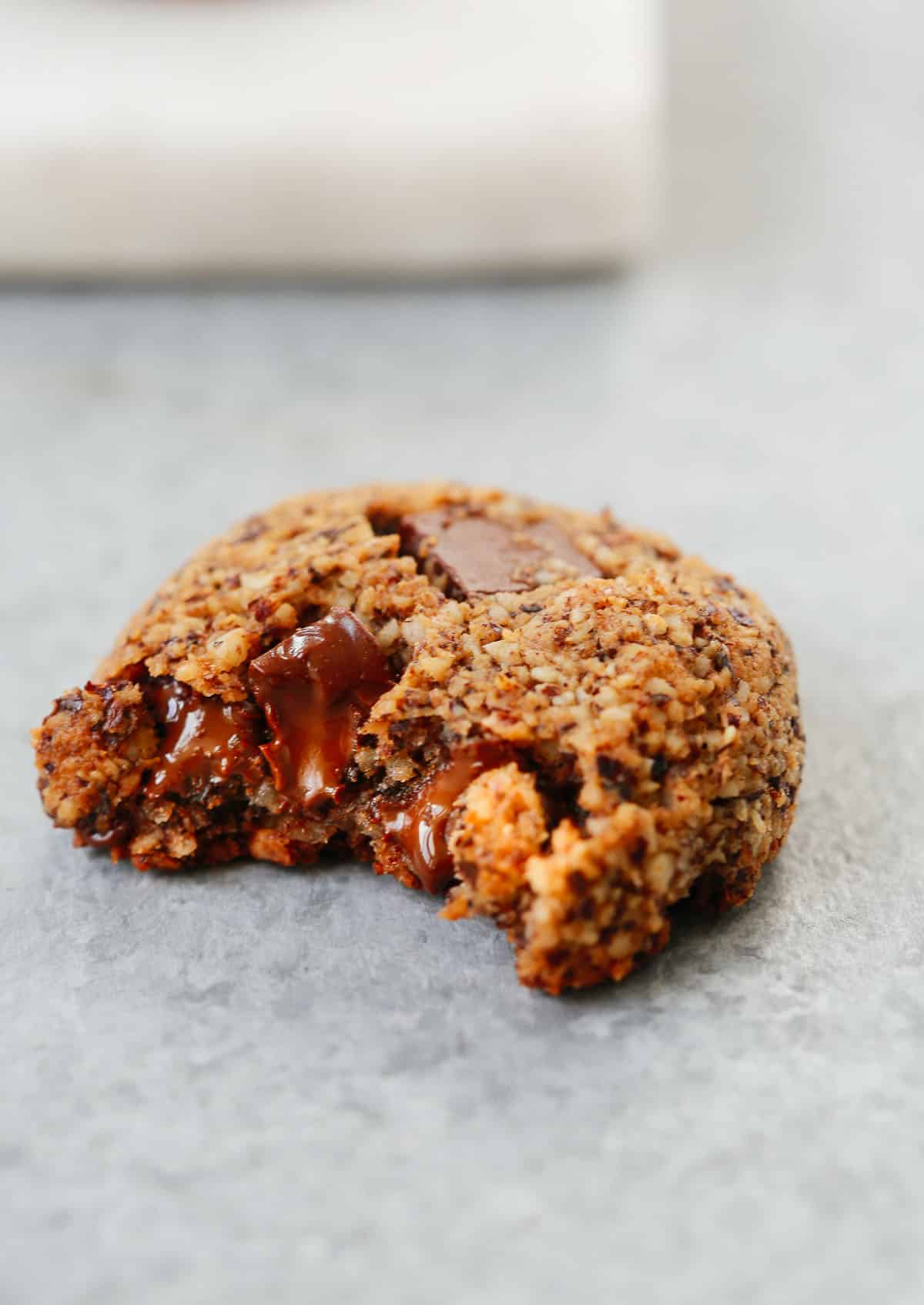 A photo of Chocolate Chunk Hazelnut Cookies with a bite taken out of it.