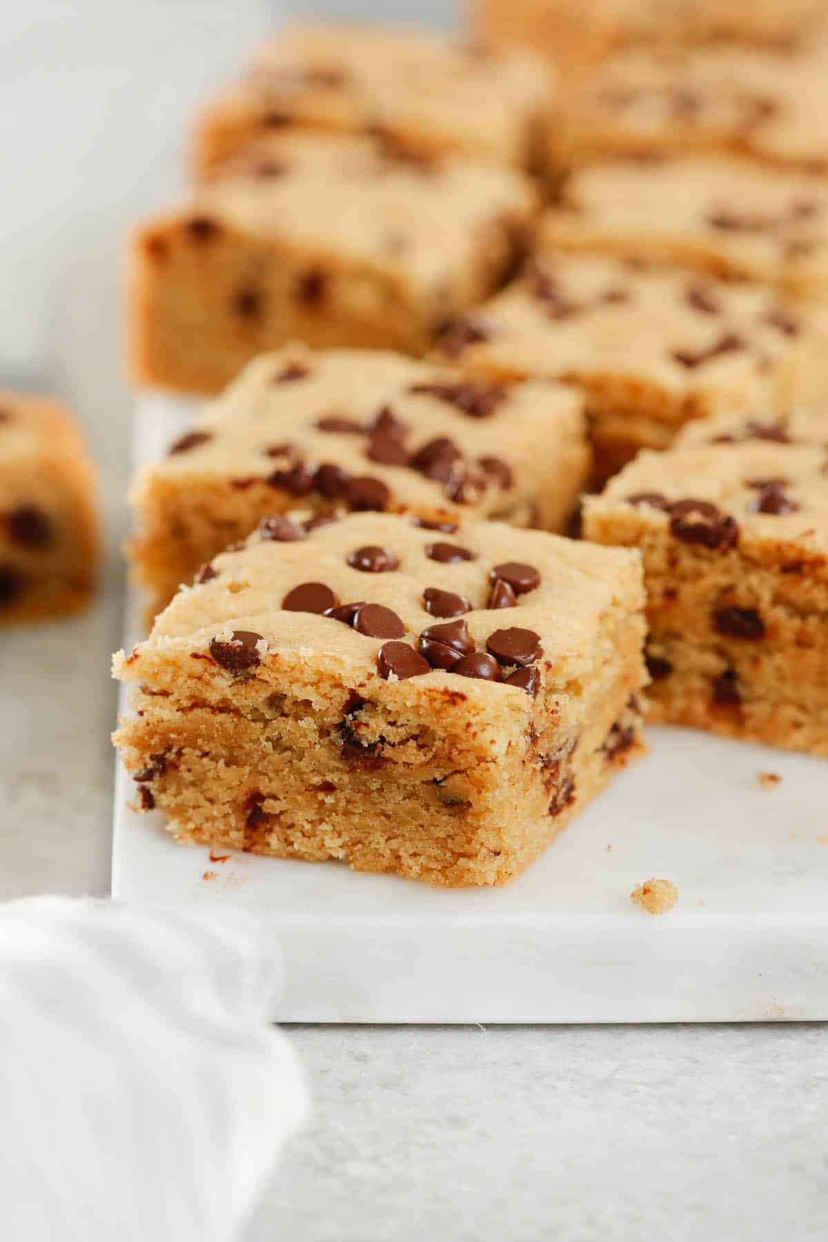 Close up of healthier chocolate chip cookie bars on a marble serving board.