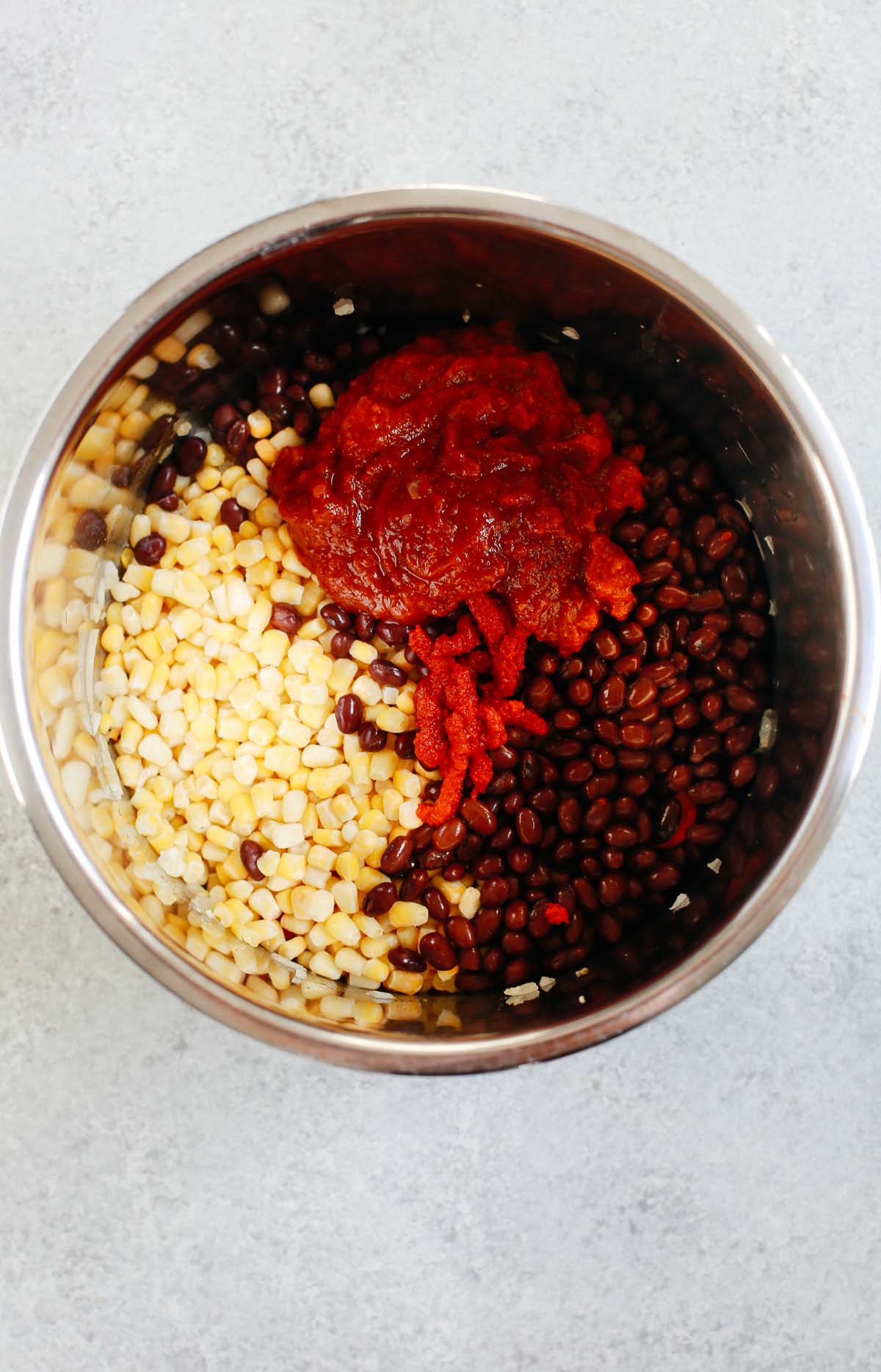 An instant pot liner with corn, black beans, tomato sauce, and tomato paste added in.