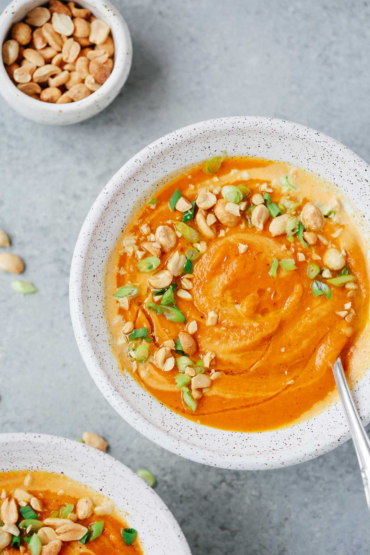 Overhead view of a bowl of spicy carrot soup with a spoon inside.