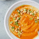 Spicy carrot soup in a speckled bowl.