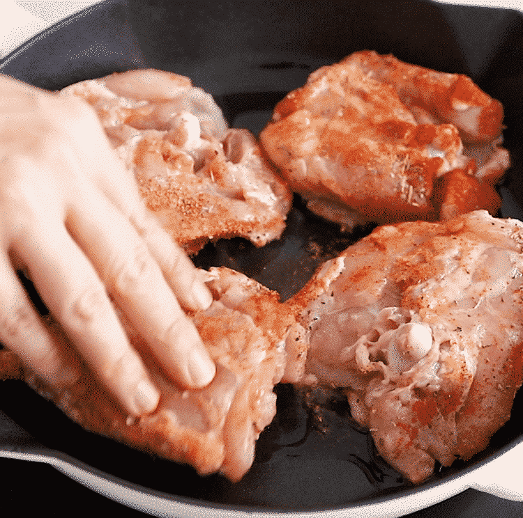 close up of cast iron skillet containing chicken thighs