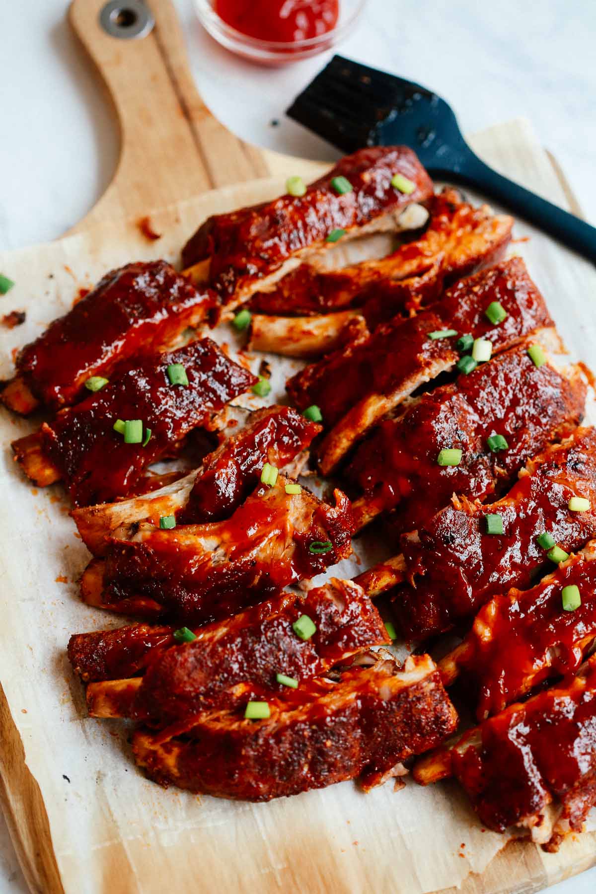 Oven baked ribs on top of a cutting board.