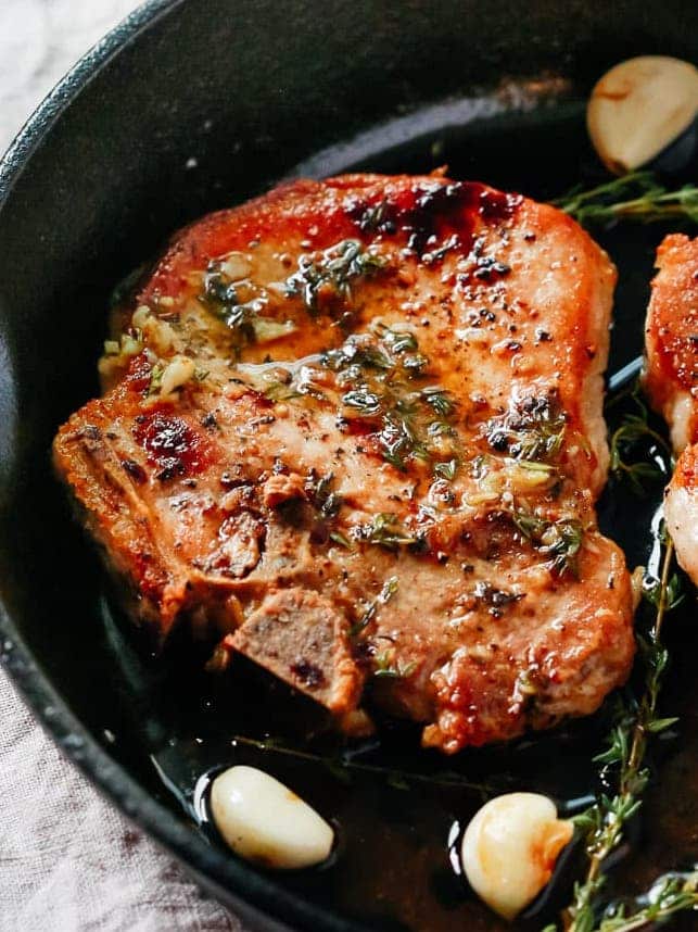 overhead view of a white skillet containing pork chops