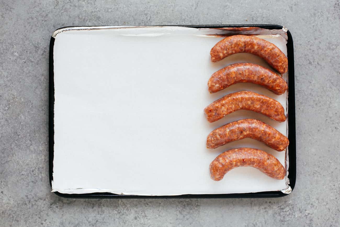 A sheet pan with five sausages.