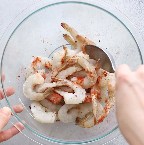 overhead view of a large glass bowl containing shrimp and spices